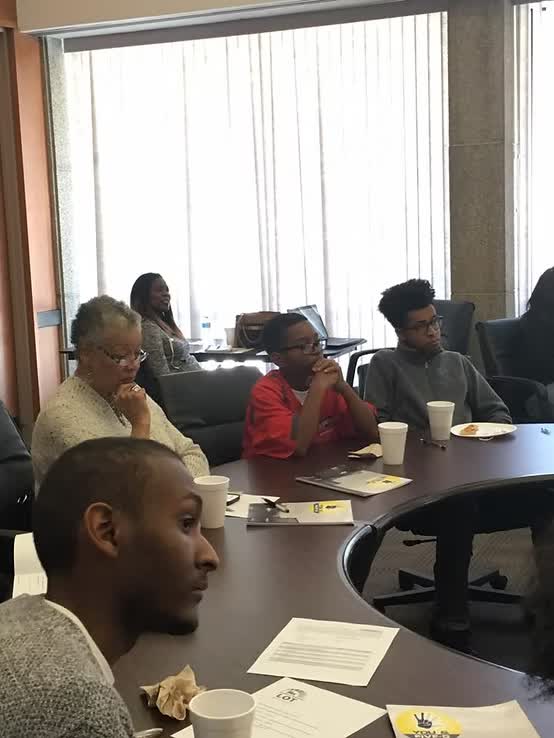 Community members seated around a roundtable with You & Five-O materials